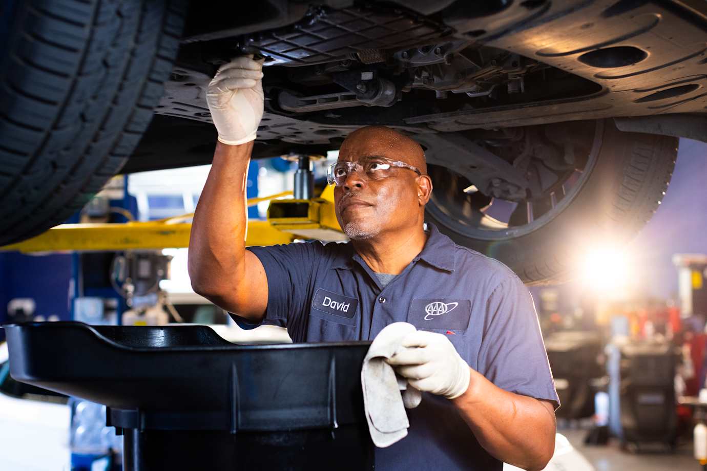 ASE-certified technician servicing a vehicle on a lift in a repair bay